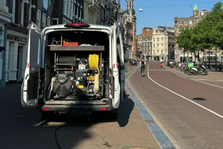 Servicebus van Rioolned met rioolreinigings- en inspectieapparatuur, geparkeerd langs een gracht voor een rioolinspectie