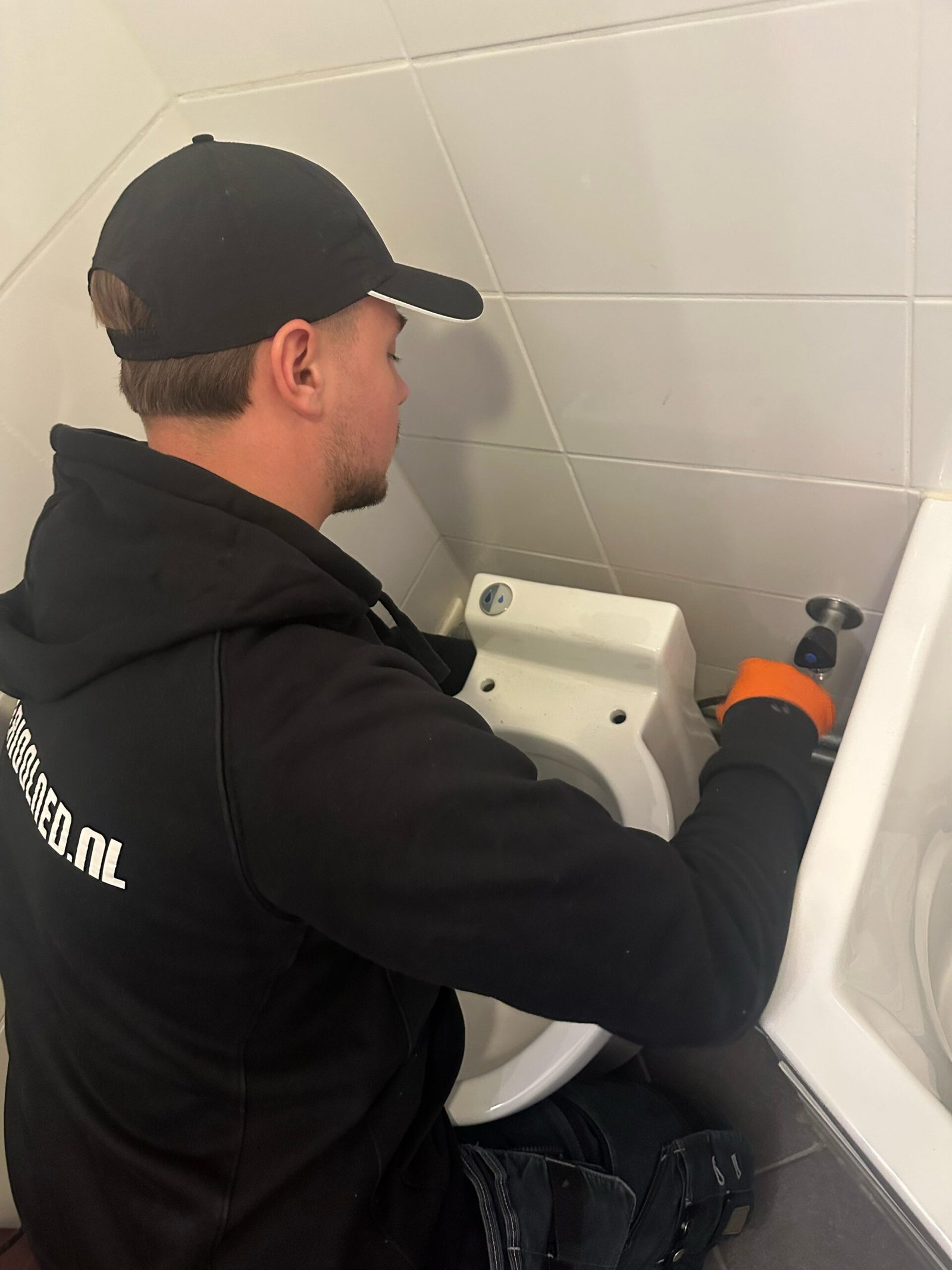 Monteur van Rioolned werkt aan de afvoer van een douche