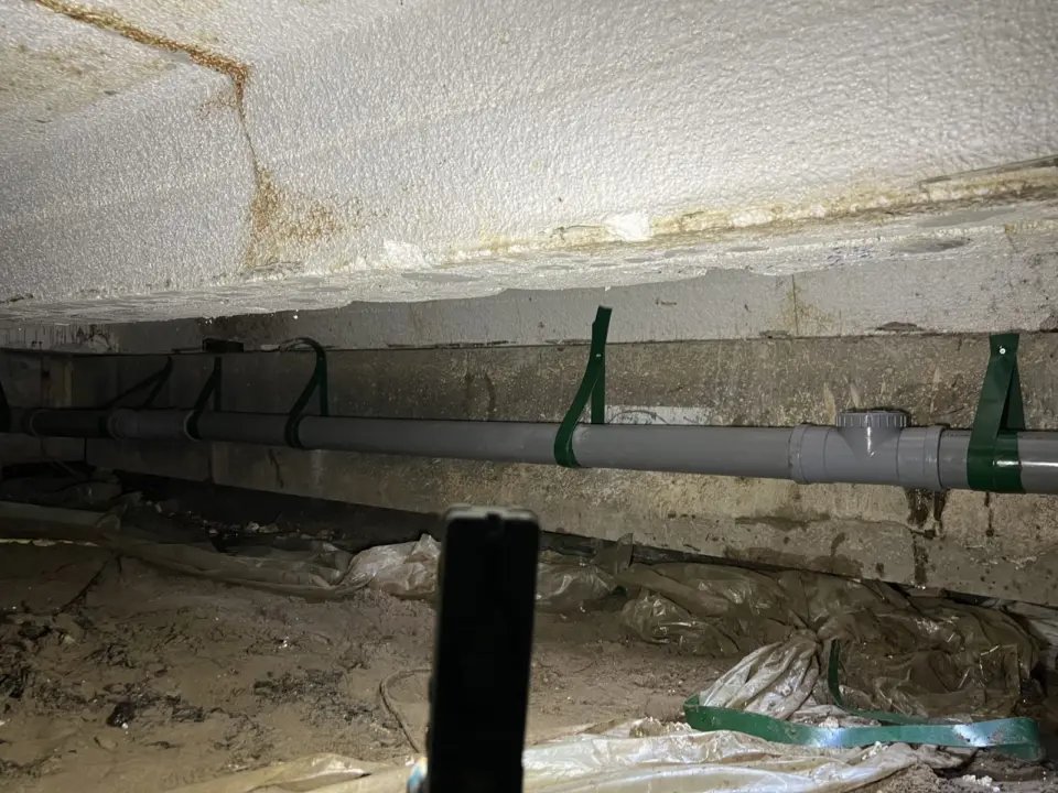 Pvc-leiding in een kruipruimte, opgehangen aan beugels